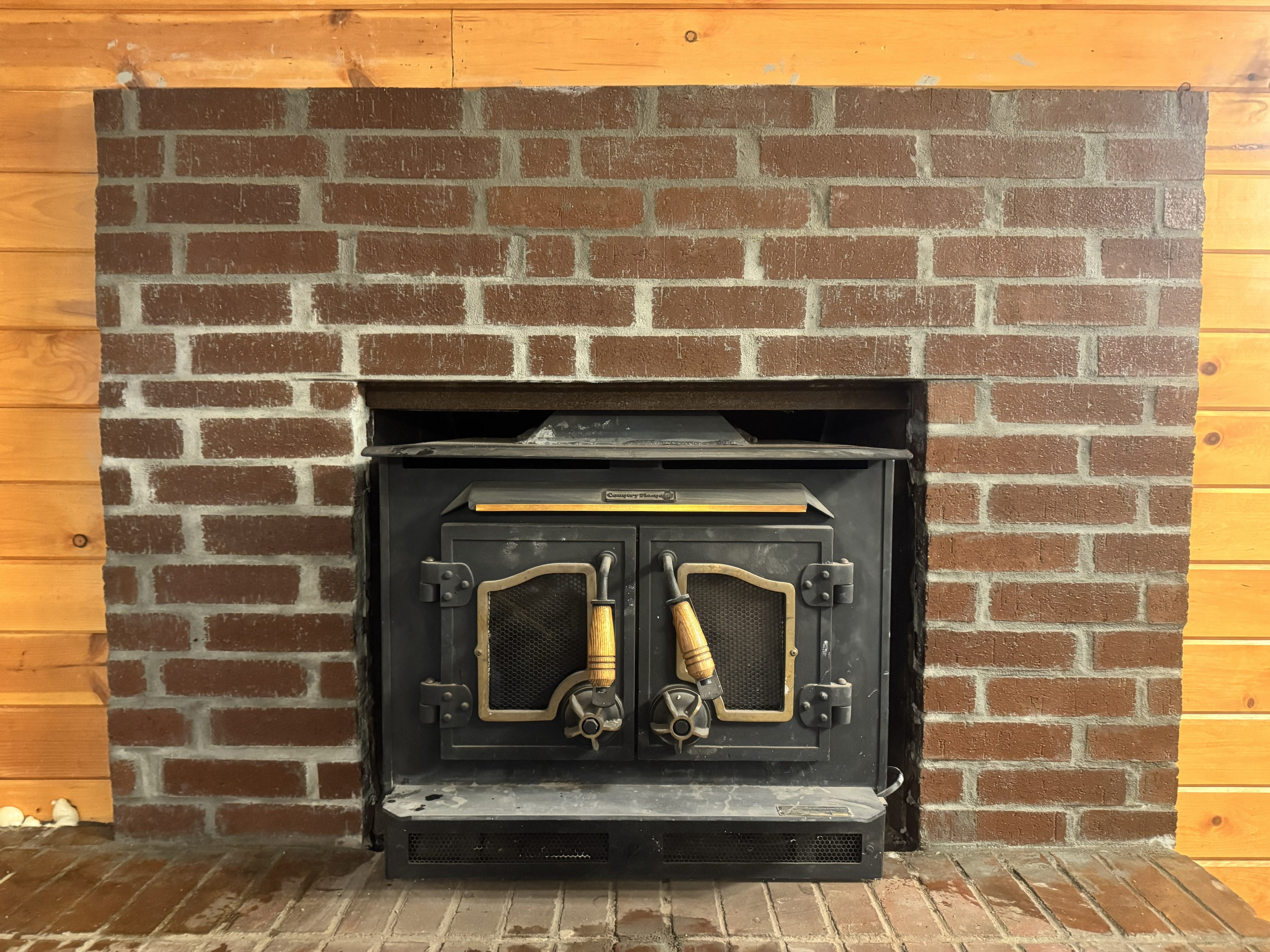 Fireplace restoration with brick surround and wood stove insert by Jill Of All Trades